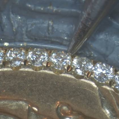 Row of diamonds being set by hand under the microscope