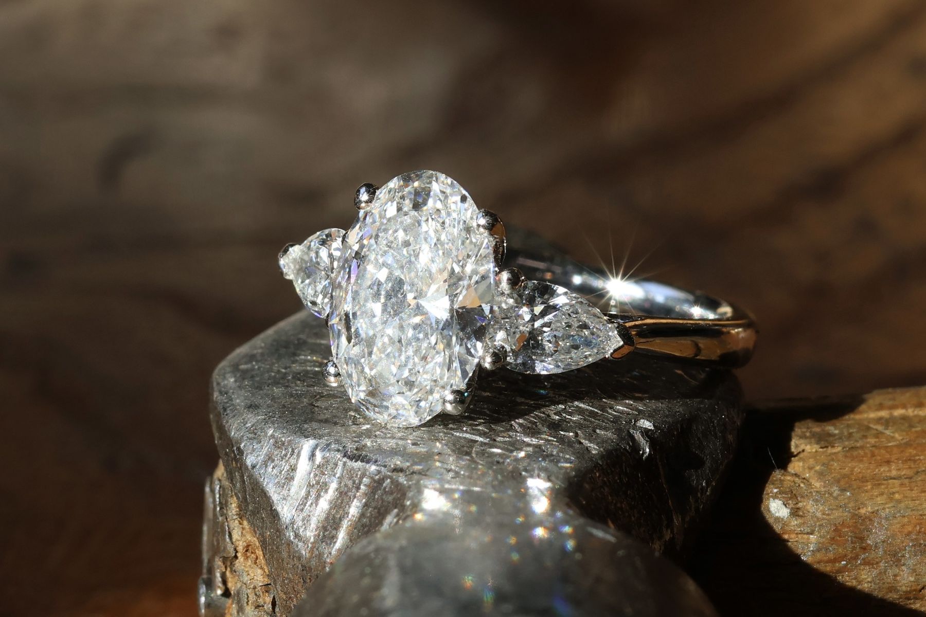Oval cut diamond engagement ring with pear cut shoulder stones, set by hand in platinum and gold