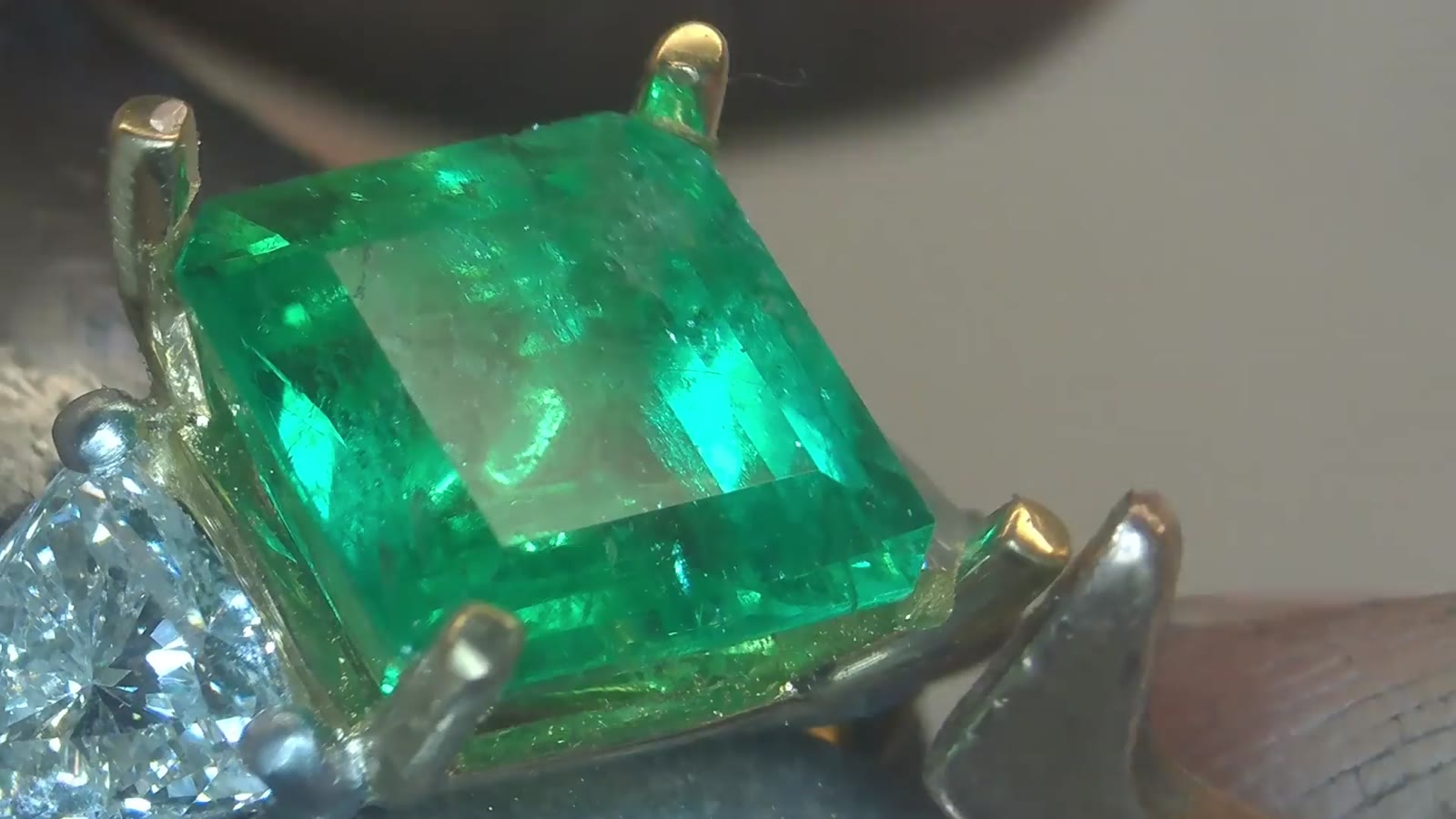 Emerald cut green stone held in claw settings, seen under the microscope